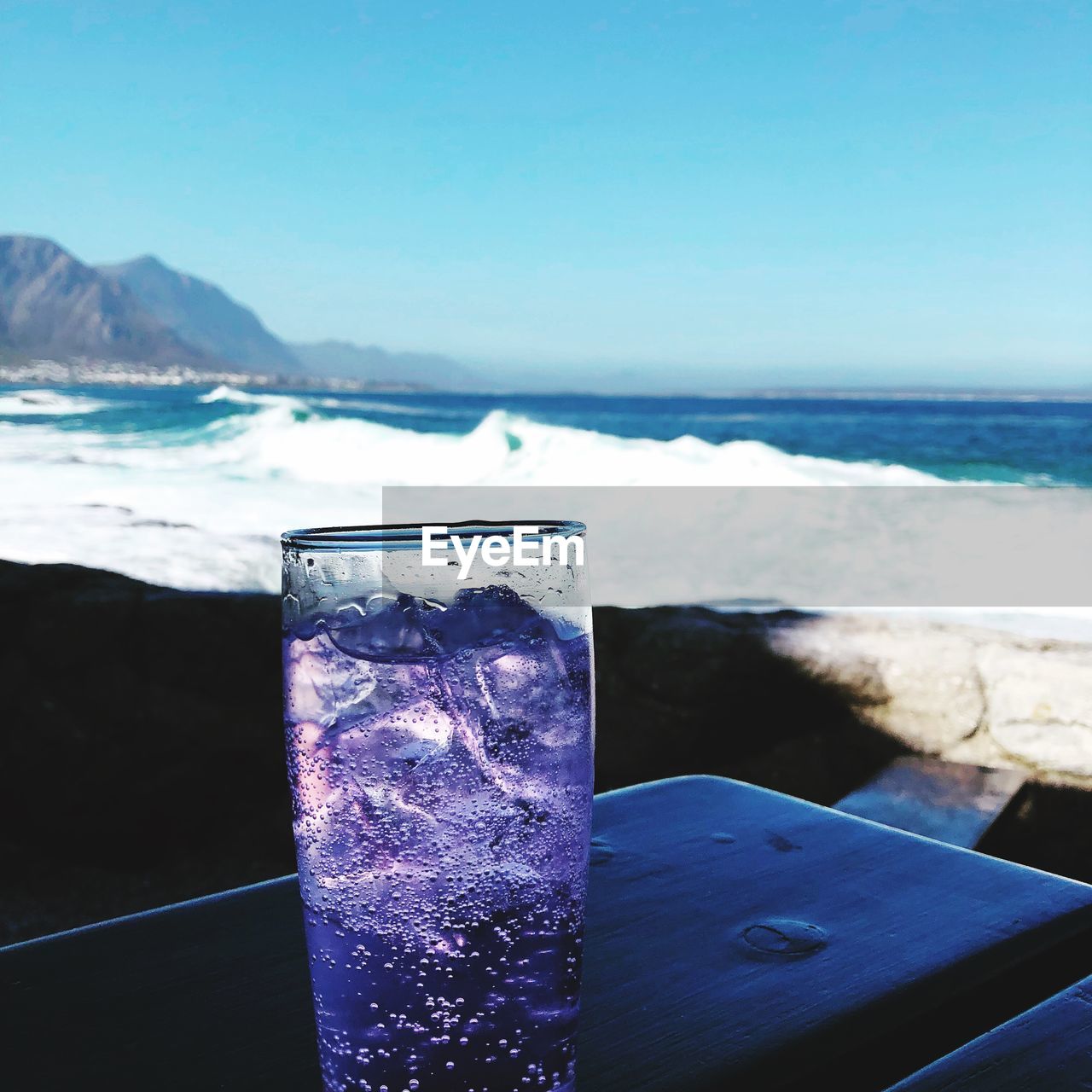 Close-up of drink against sea during sunny day