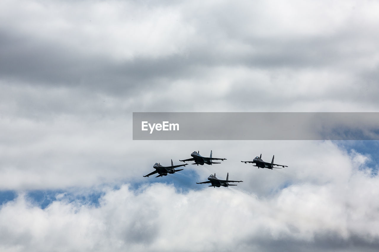 Low angle view of fighter planes flying against cloudy sky