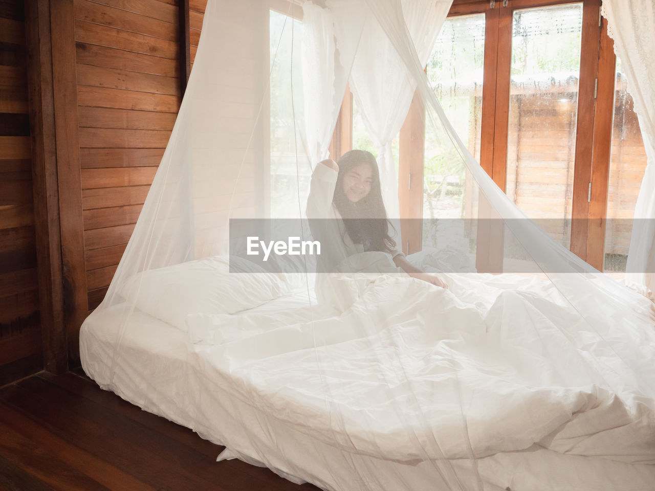 Woman stretching in bed after wake up, happy greets new day with warm sunlight.