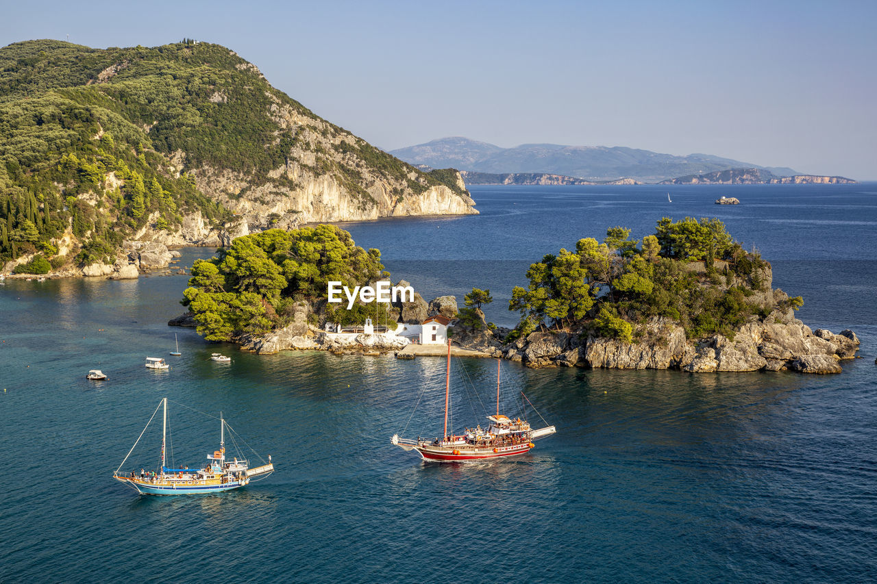 Greece, preveza, parga, ships sailing in front of panagia chapel in summer