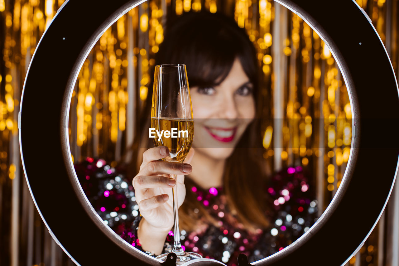 Portrait of smiling young woman with champagne against decorations