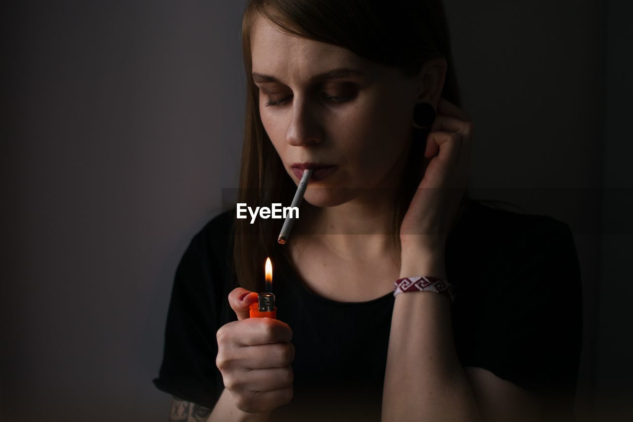 Woman smoking cigarette against black background