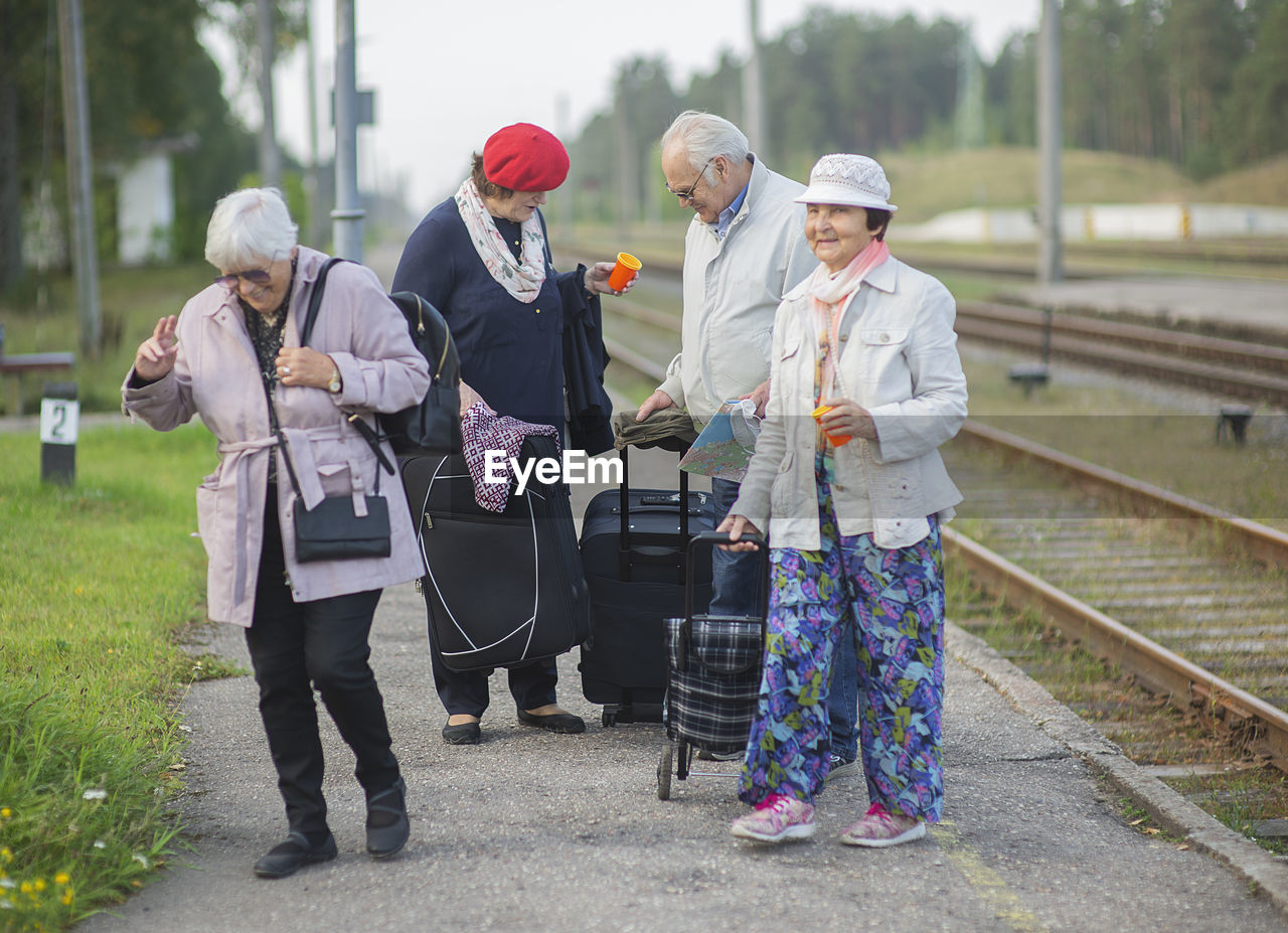 Group of positive elderly seniors people waiting train before traveling during a pandemic