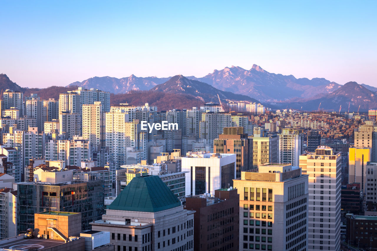 Aerial view of buildings in city against clear sky