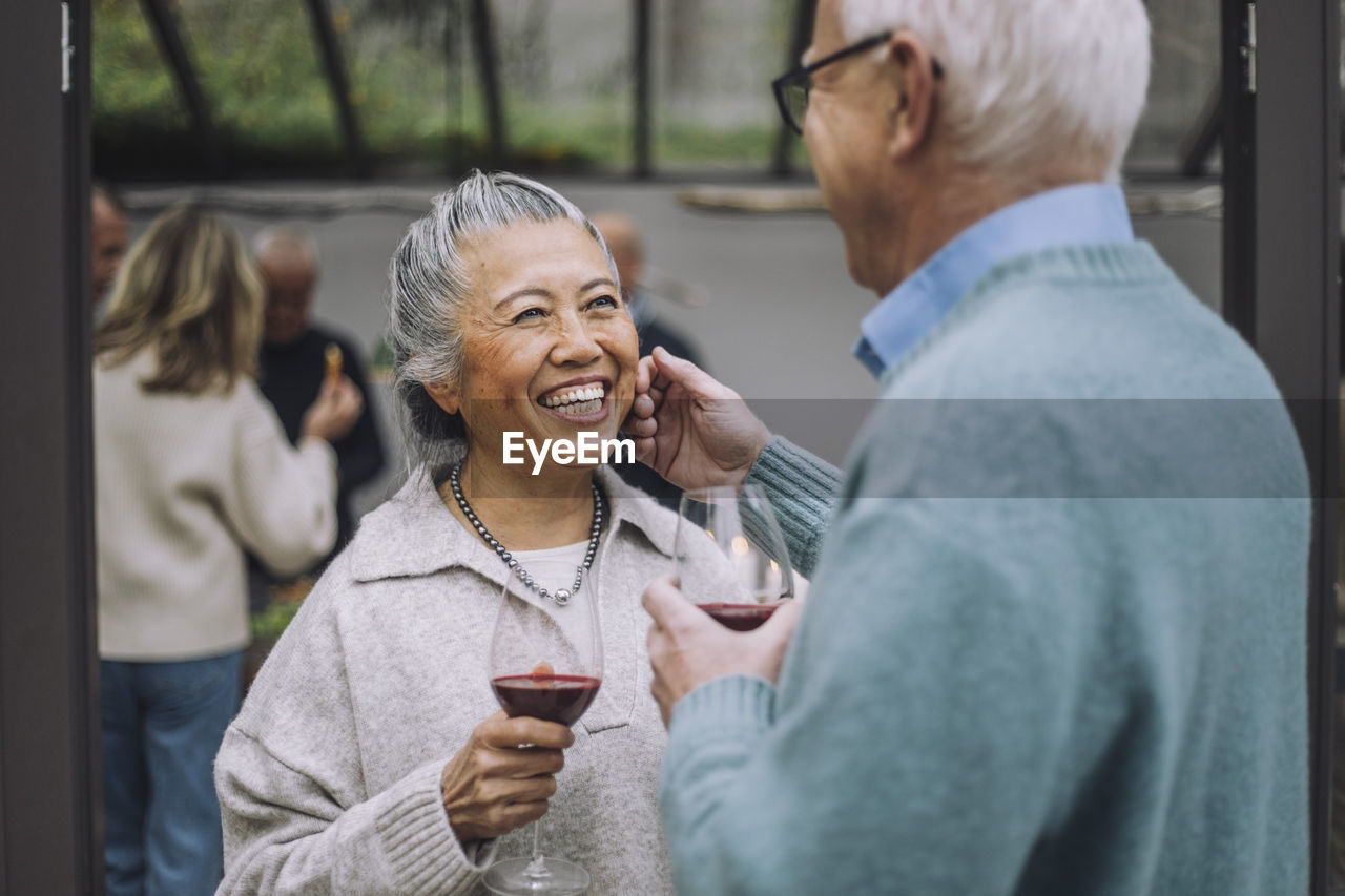 Senior man touching face of happy female friend at dinner party