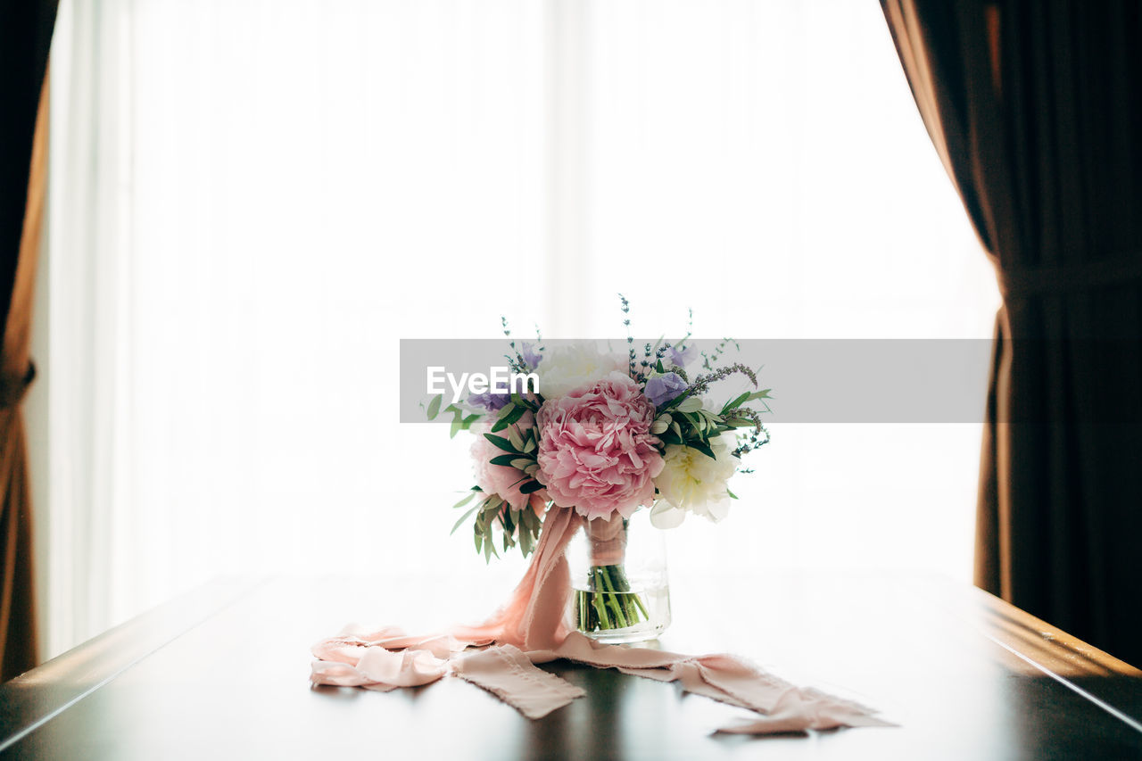 Flower vase on table against window