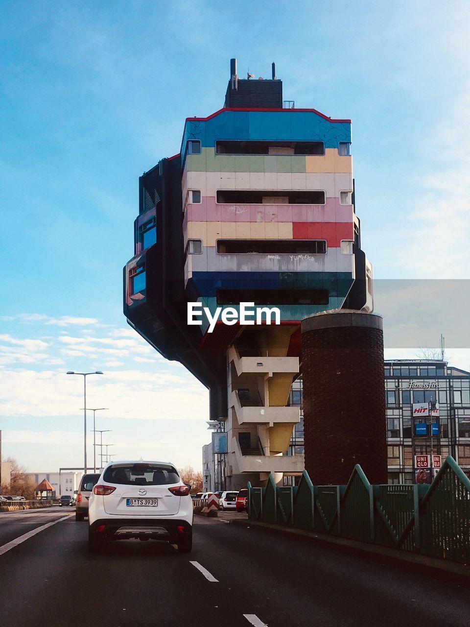 VEHICLES ON ROAD BY BUILDINGS AGAINST SKY