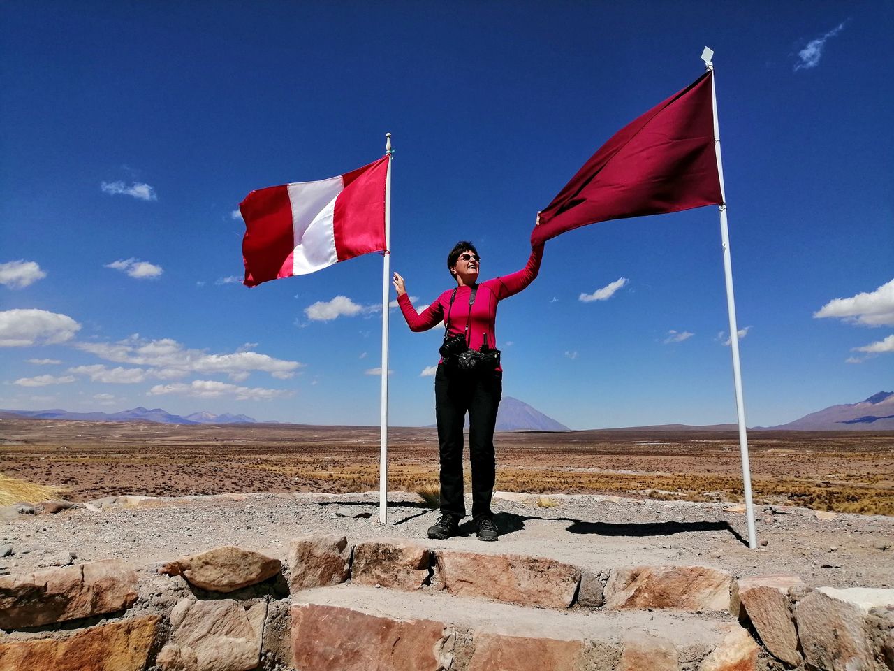 Senior woman holding peruvian flag in high plain of patahuasi, peru