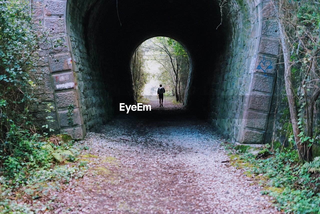 REAR VIEW OF PERSON STANDING AMIDST TUNNEL