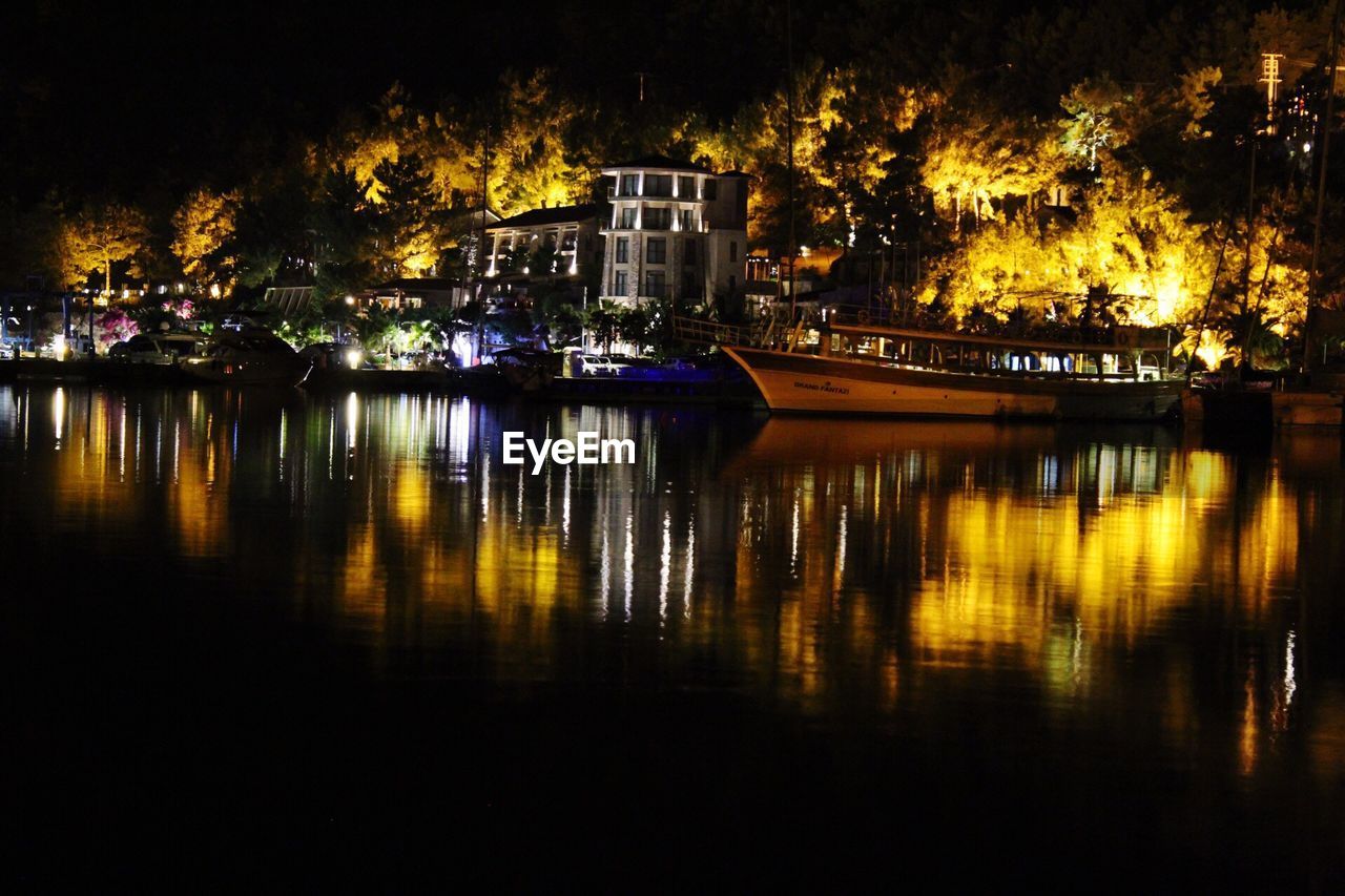 ILLUMINATED BUILDINGS BY RIVER AT NIGHT