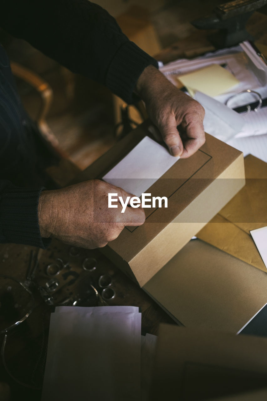 Male entrepreneur's hands labeling on box at workshop