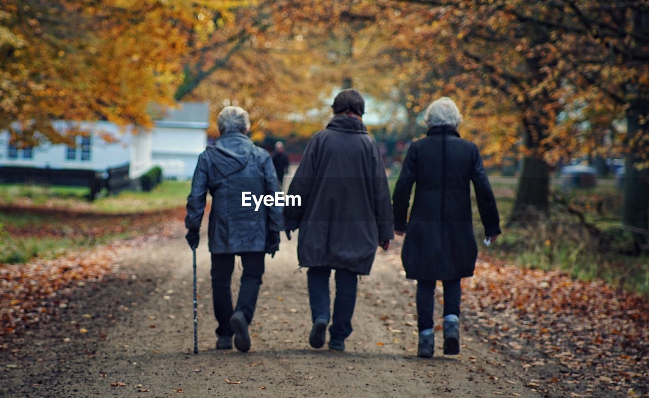 Rear view of women walking on footpath during winter