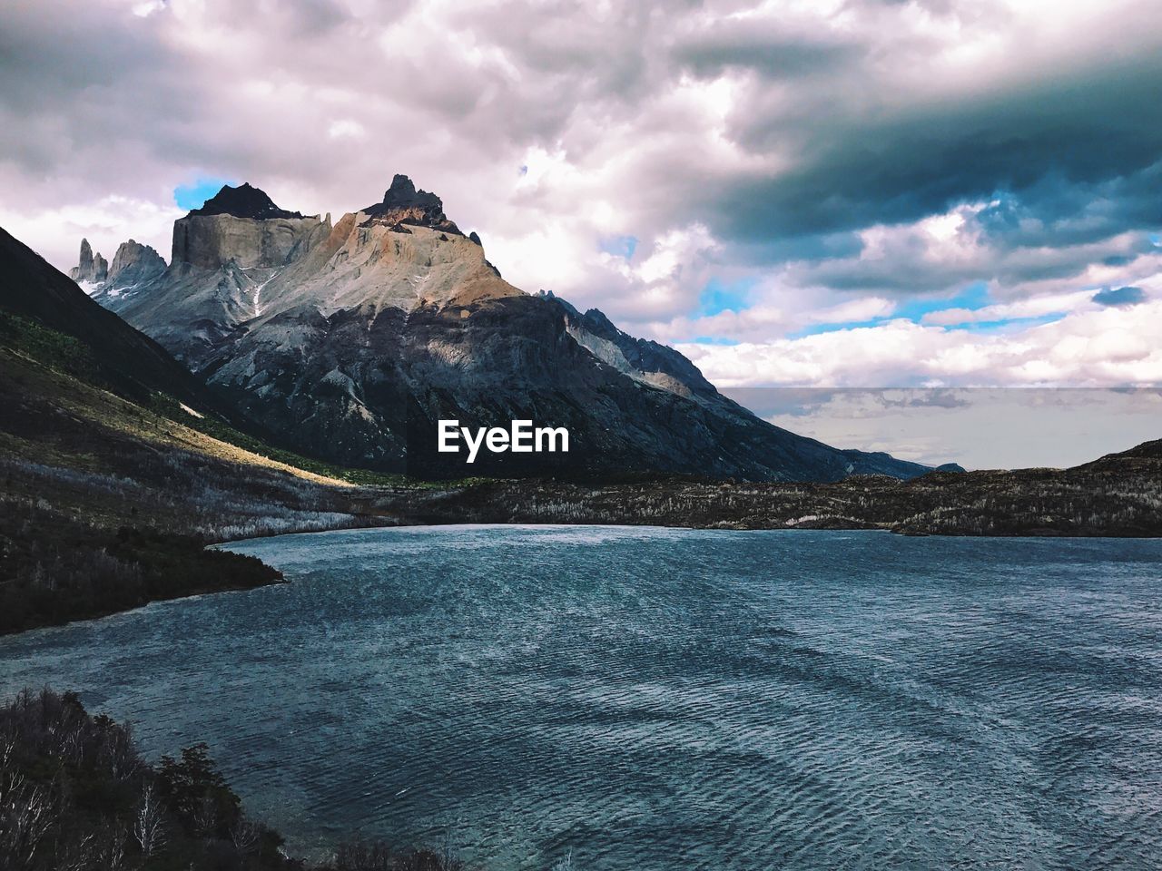 Scenic view of lake and mountains against dramatic sky