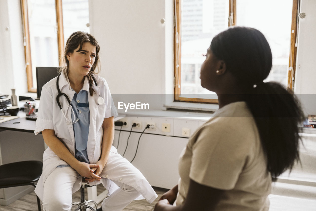 Female doctor discussing with patient while consulting in medical clinic