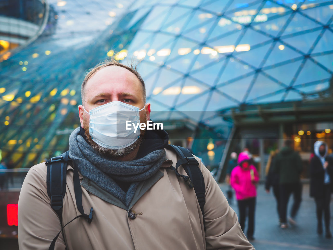 Adult european man wearing a mask outdoor near shopping center in a city