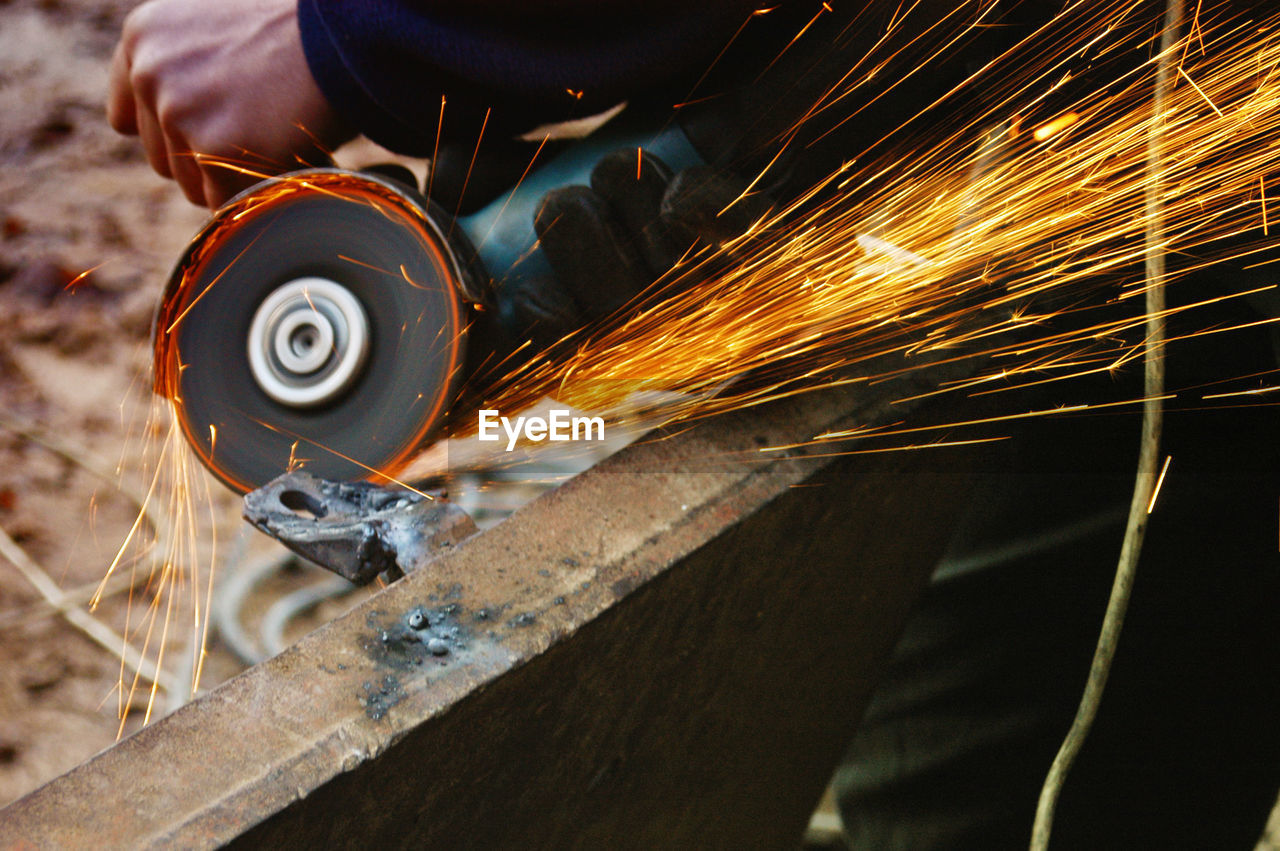 Midsection of man cutting metal