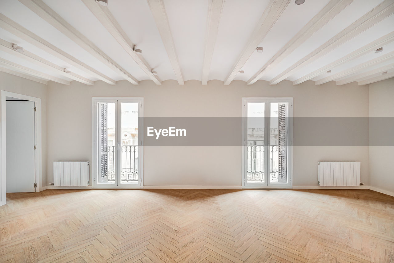 Empty and clean room in a refurbished apartment with wooden floor and two balconies