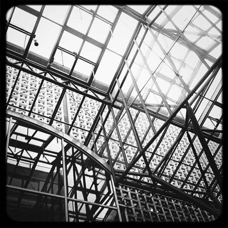 Low angle view of glass ceiling of building against clear sky