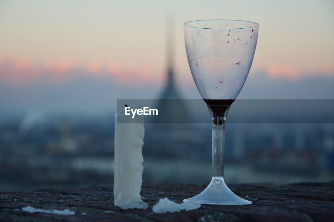 Close-up of wine glass and candle against sunrise in turin