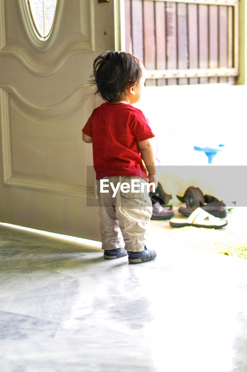 Rear view of boy standing by door at home