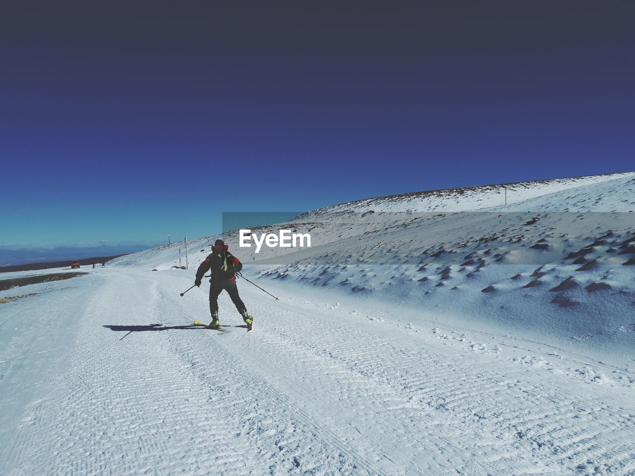 Rear view of man skiing on snowcapped mountain against clear sky