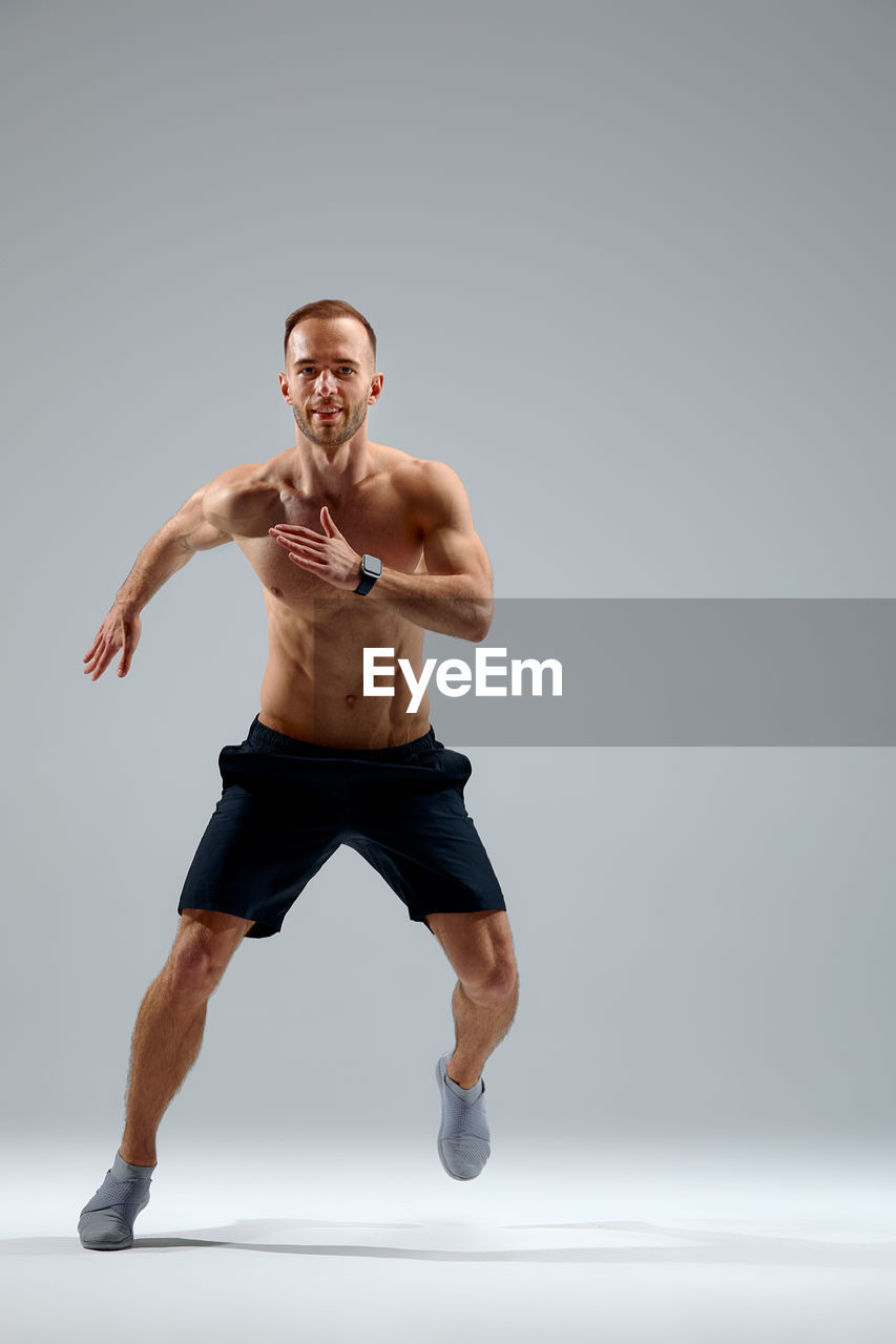 portrait of shirtless man exercising against white background