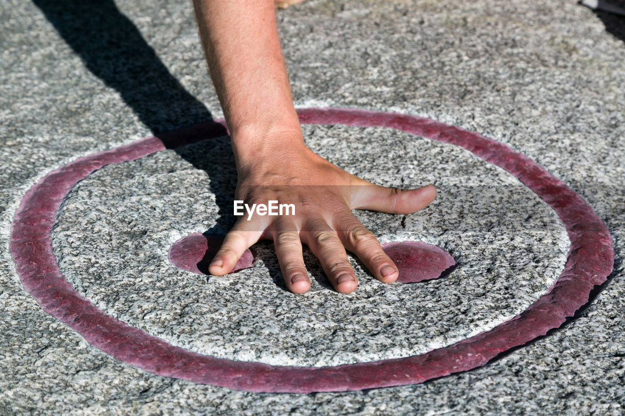 Cropped hand of man touching symbol on floor