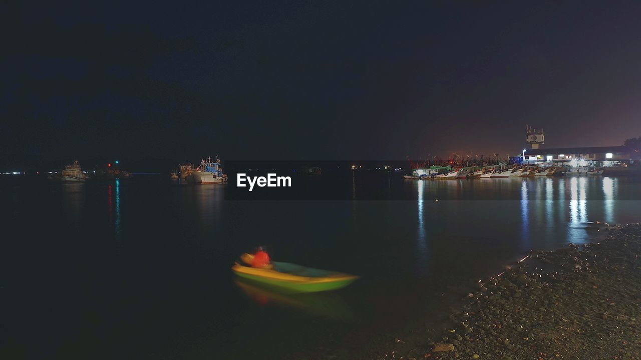 Boats moored in sea against sky at night