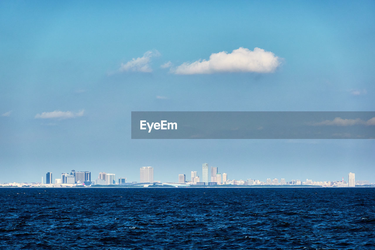 Sea by buildings against sky in city