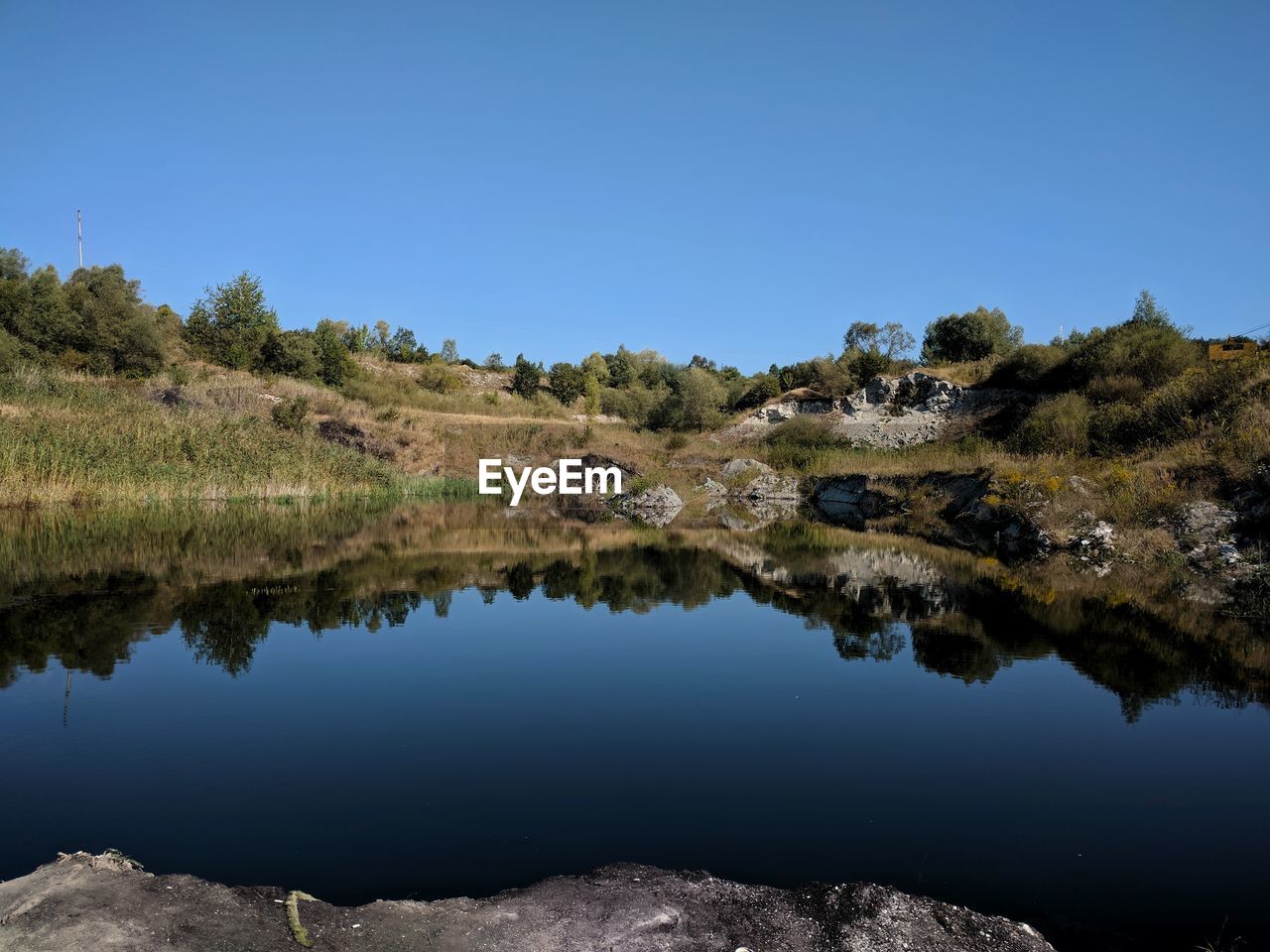 Scenic view of lake against clear blue sky