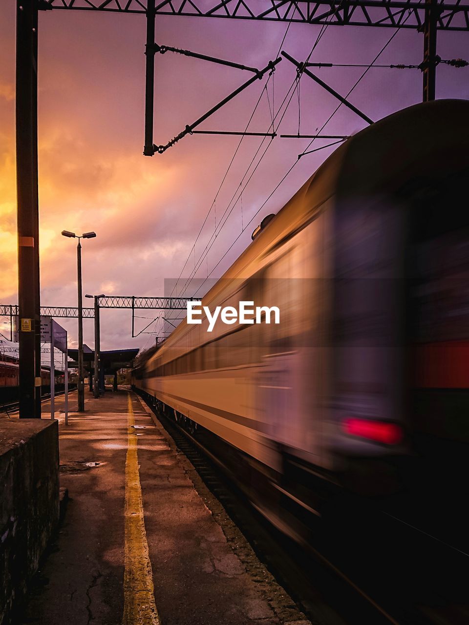 Blurred motion of train at railroad station against sky during sunset