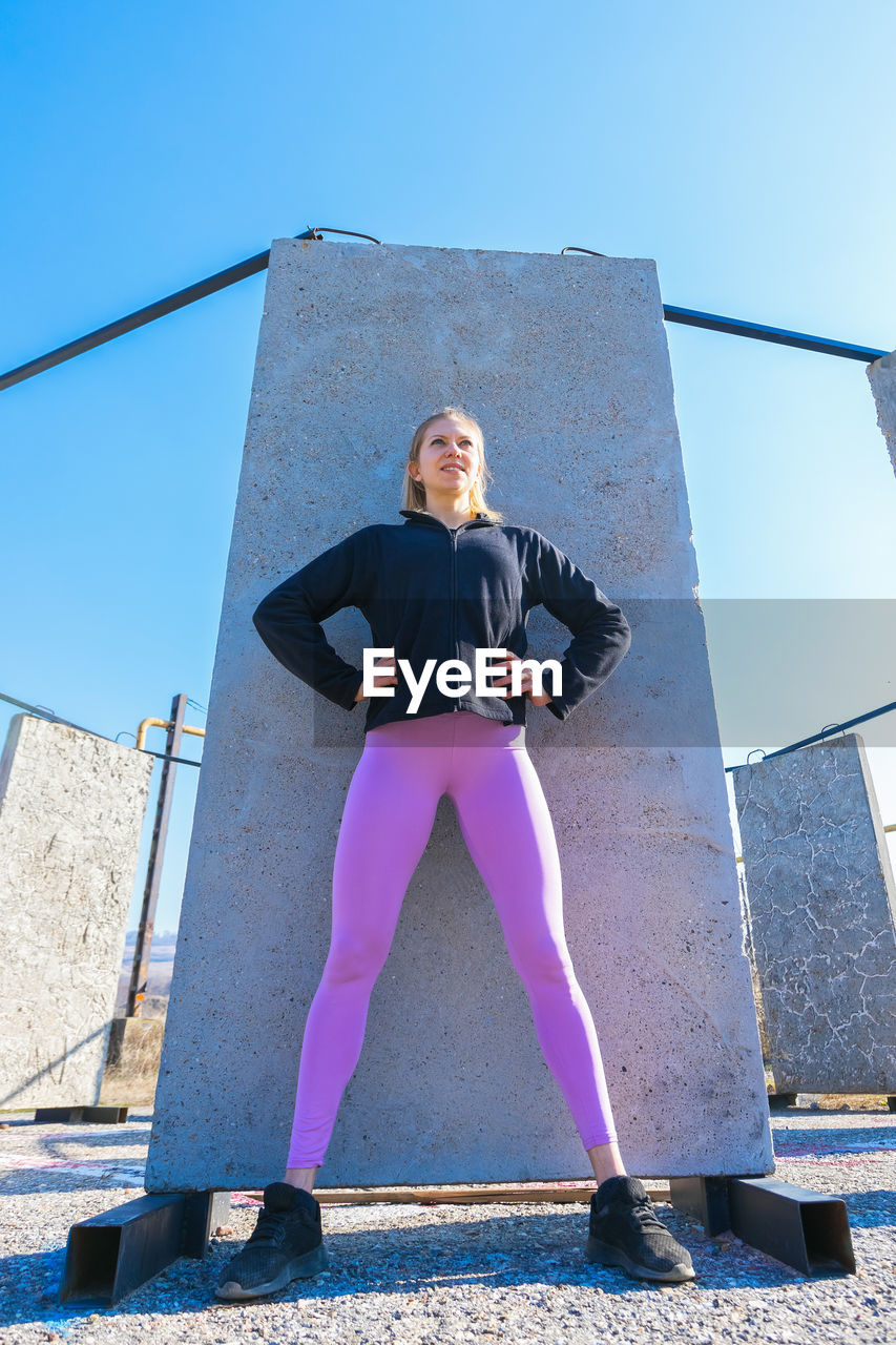 FULL LENGTH OF YOUNG WOMAN STANDING AGAINST SKY