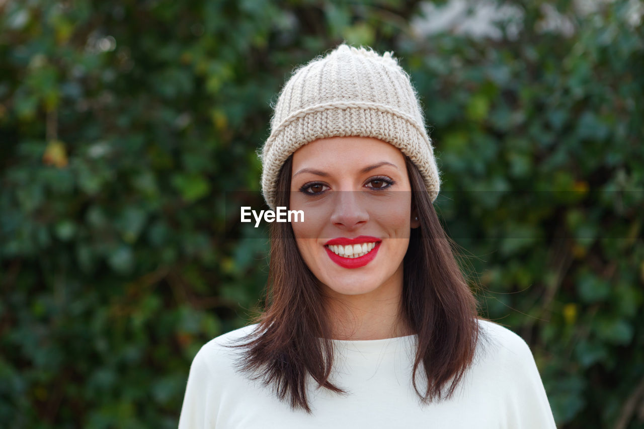 Portrait of smiling woman standing against trees