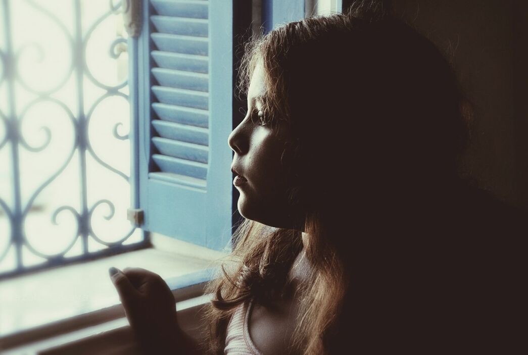 Close-up of a girl looking through window