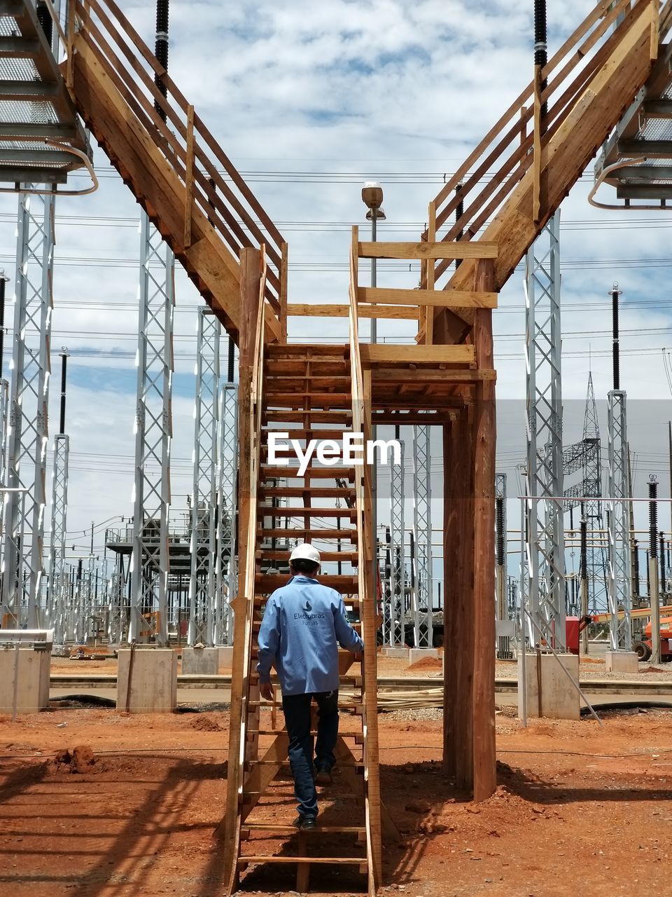 Rear view of male worker moving up on staircase at factory