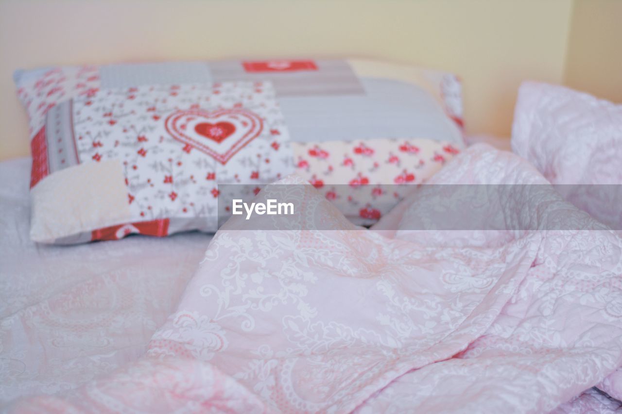 CLOSE-UP OF BED WITH PINK PETALS ON BLANKET