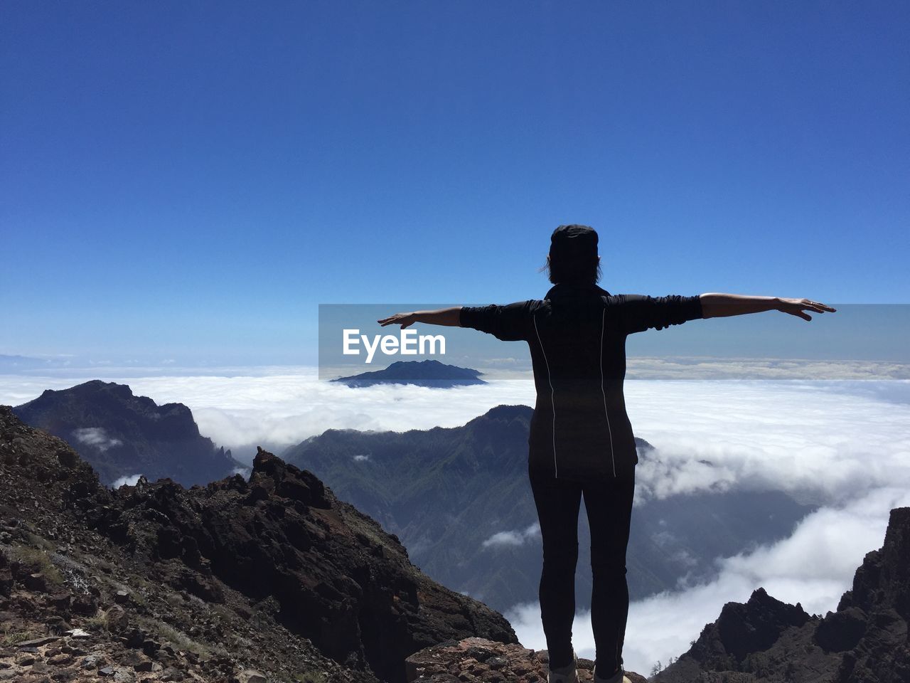 Rear view of woman with arms outstretched standing on mountain