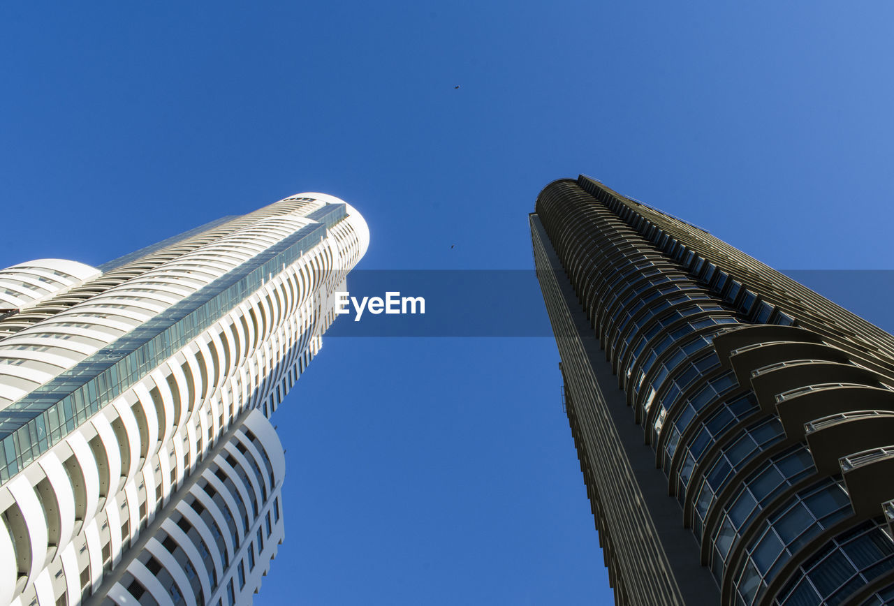 Low angle view of modern buildings against clear blue sky