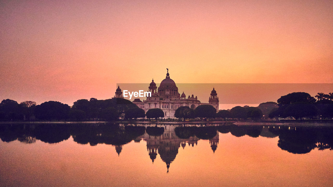 Reflection of historic building in lake during sunset