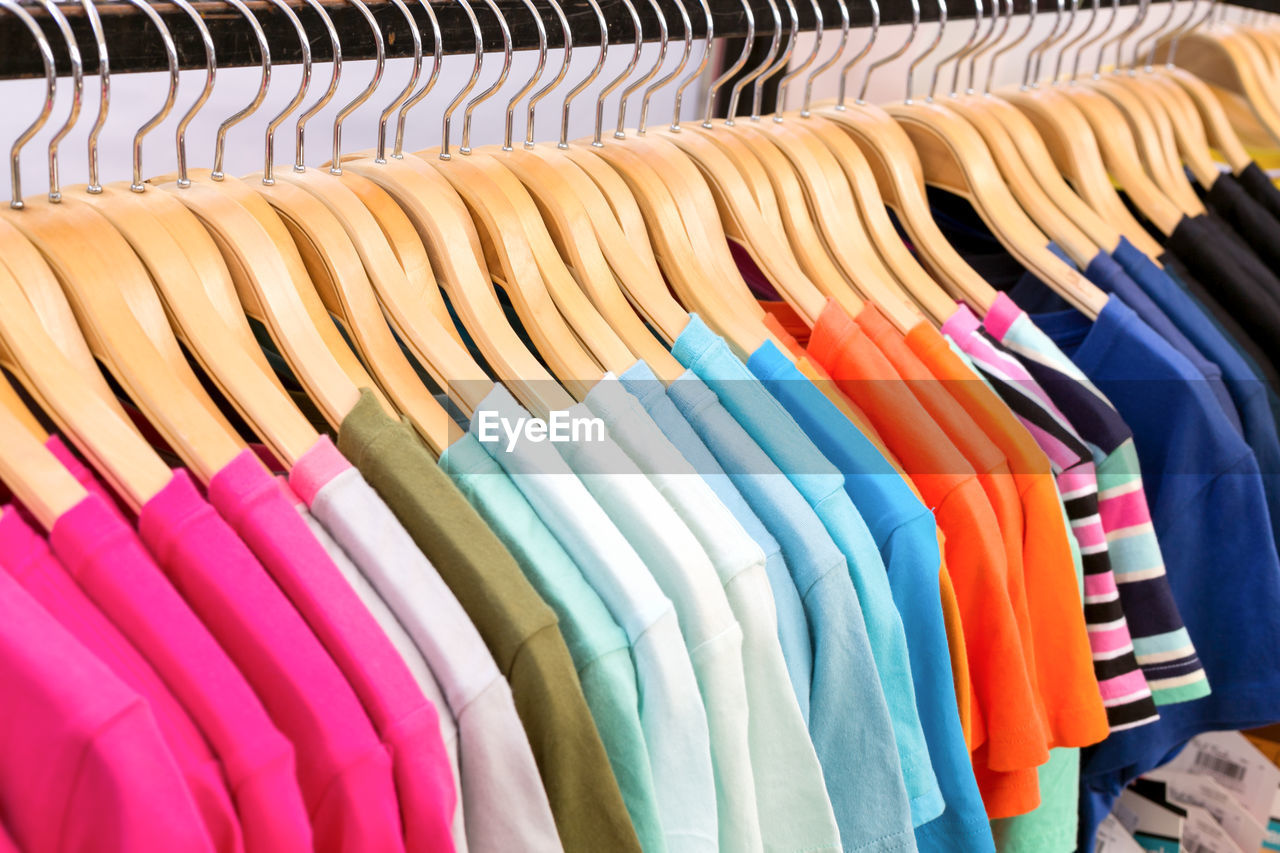 Close-up of colorful t-shirts hanging on rack in store