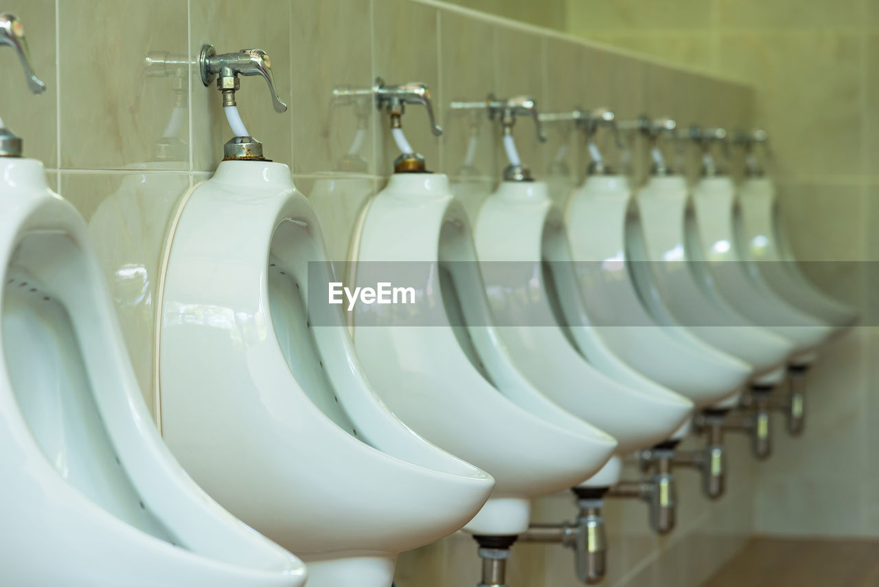 Toilet bowls mounted on wall in public restroom