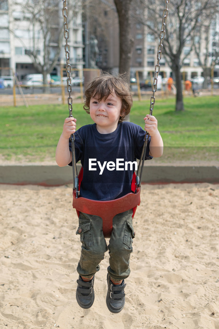 portrait of boy swinging at playground