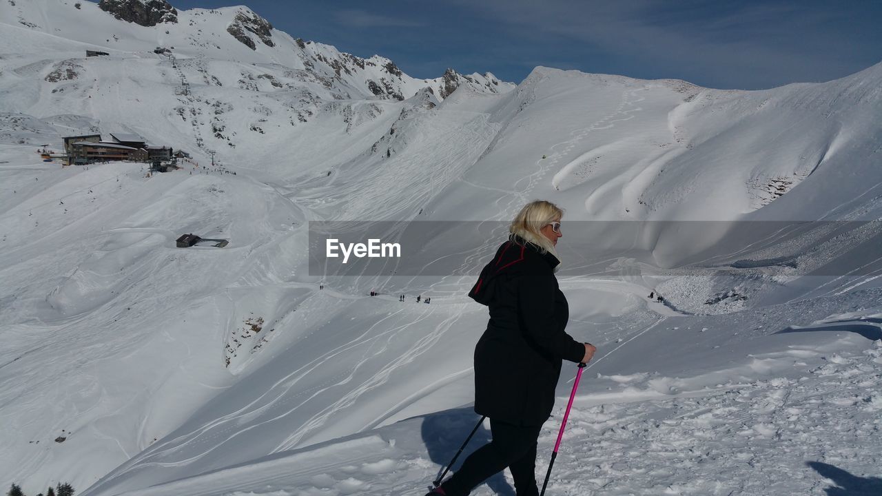 FULL LENGTH OF WOMAN ON SNOWCAPPED MOUNTAINS