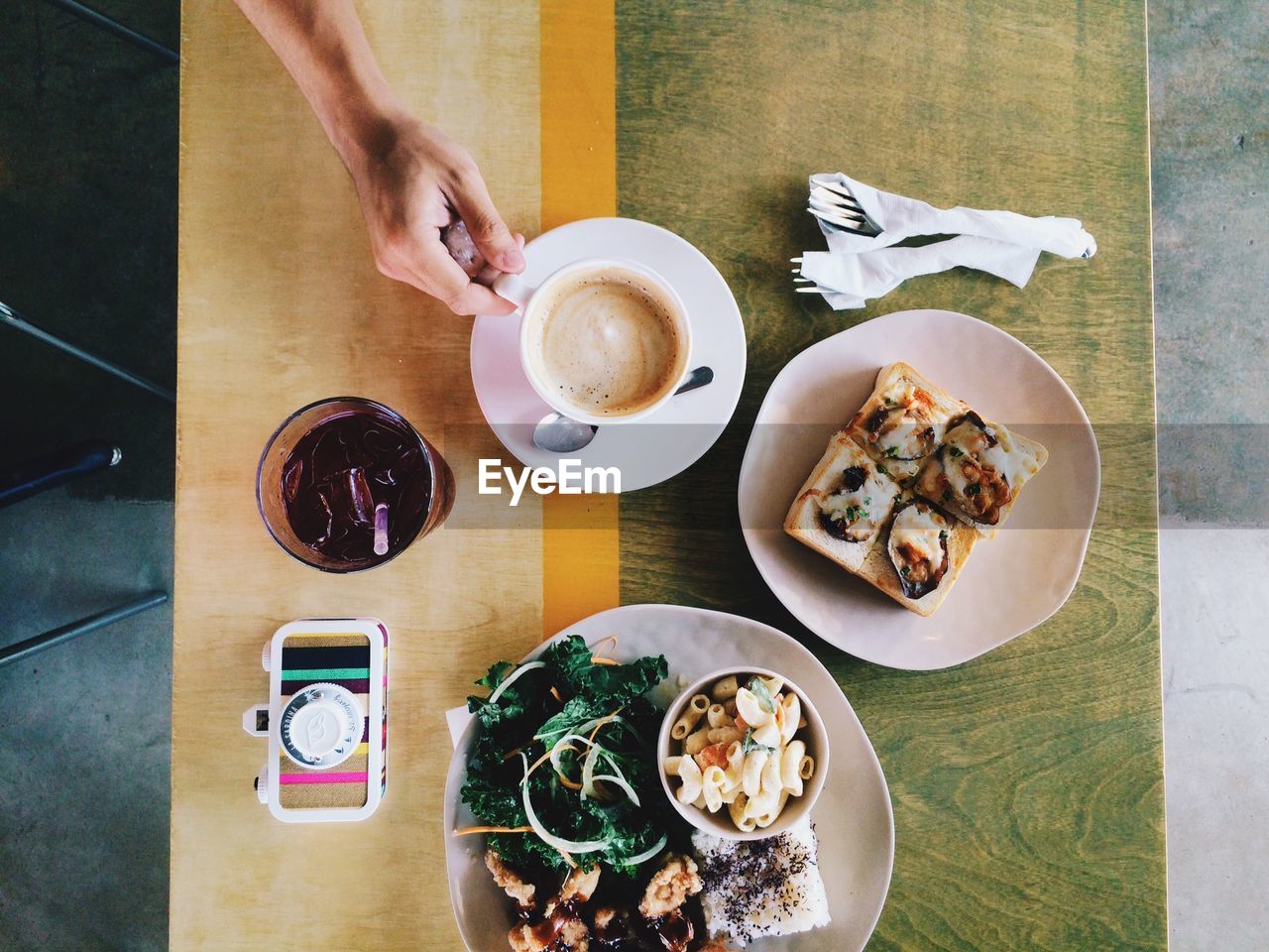 High angle view of cropped hand holding coffee cup by food served on table