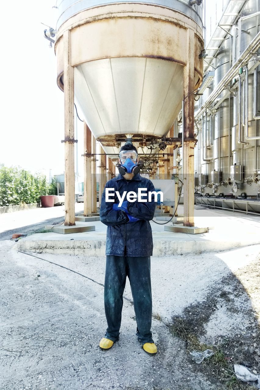 Full length portrait of man standing outside factory