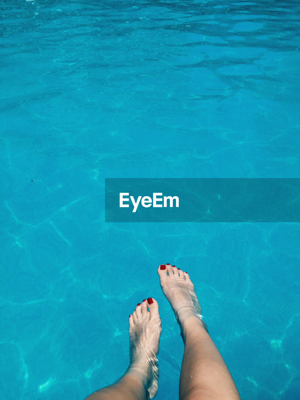 Low section of woman legs in blue swimming pool