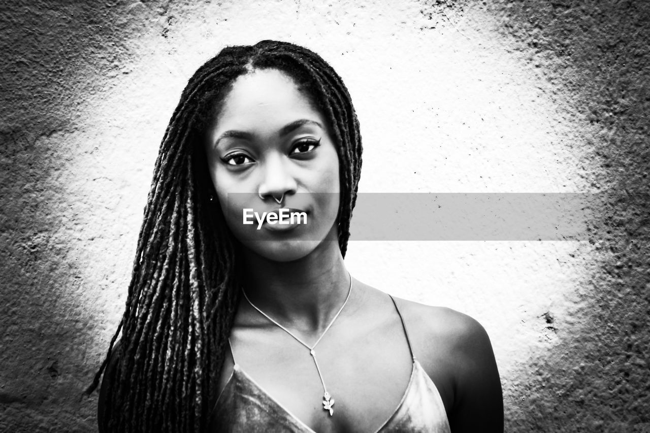 PORTRAIT OF A BEAUTIFUL YOUNG WOMAN AGAINST WALL