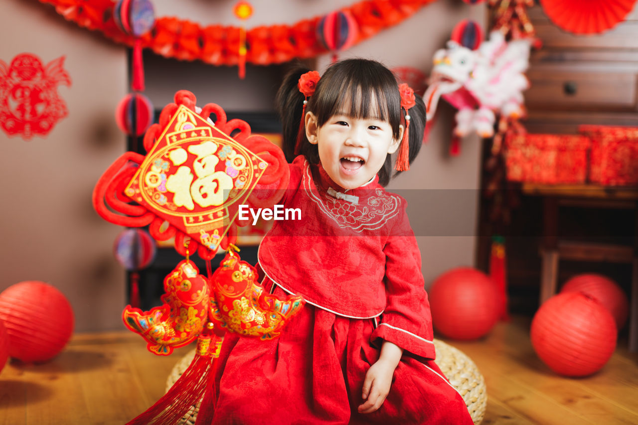 Portrait of smiling girl in traditional clothing holding decoration