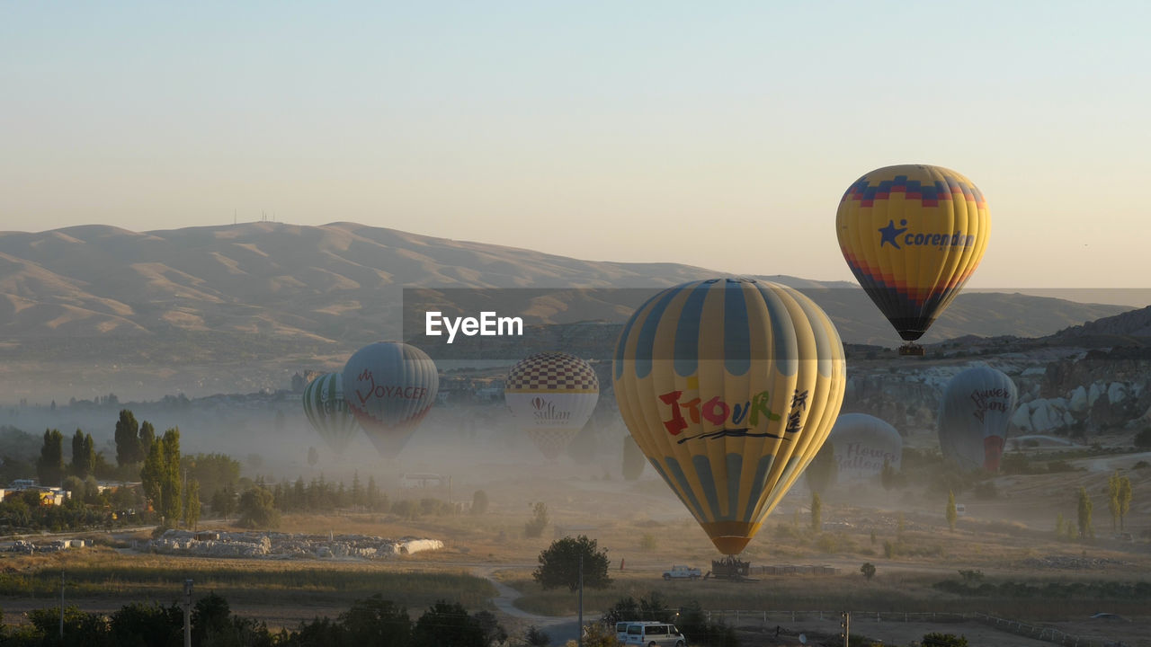 hot air balloon, balloon, air vehicle, vehicle, hot air ballooning, aircraft, transportation, mid-air, mode of transportation, travel, adventure, sky, flying, nature, ballooning festival, environment, mountain, landscape, multi colored, travel destinations, journey, scenics - nature, tourism, morning, cloud, twilight, sunrise, dawn, outdoors, tradition, toy, beauty in nature, land, no people, sun, trip, vacation, clear sky, mountain range, basket, holiday, day, leisure activity