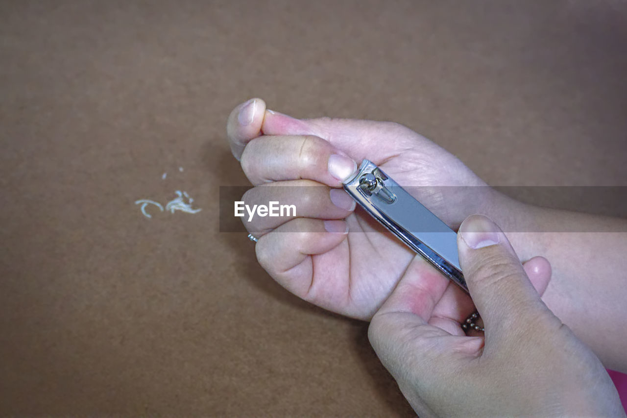 Cropped hand cutting nails on table